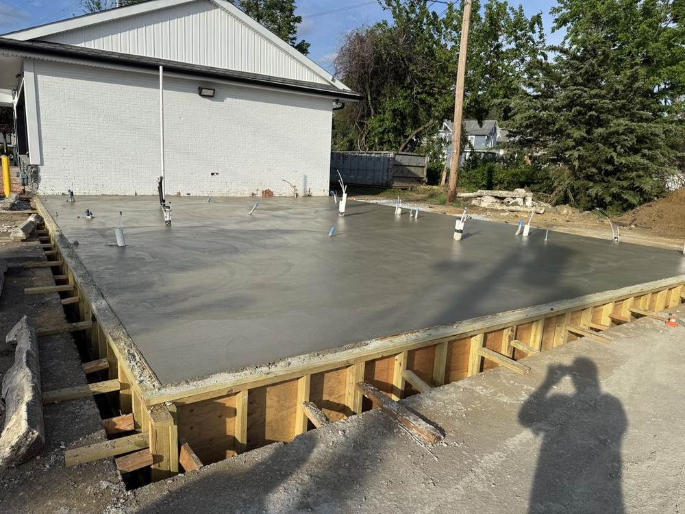 Large commercial foundation slab with wooden forms and plumbing rough-ins, fresh pour by South Jersey Construction Enterprise