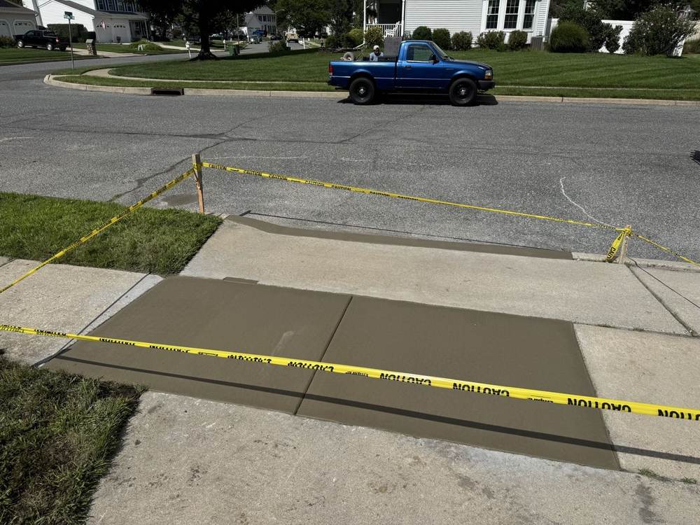 Freshly poured concrete driveway apron and sidewalk curing, completed by South Jersey Construction Enterprise