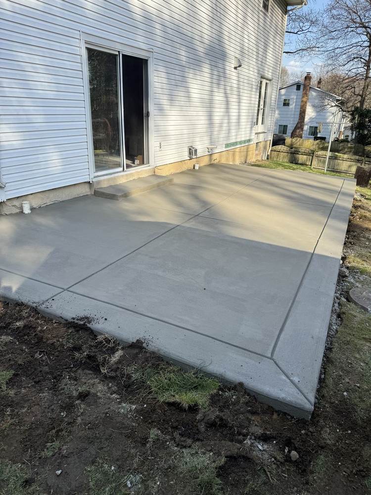 Fresh concrete driveway installed by South Jersey Construction Enterprise at a colonial house, curing behind orange cones