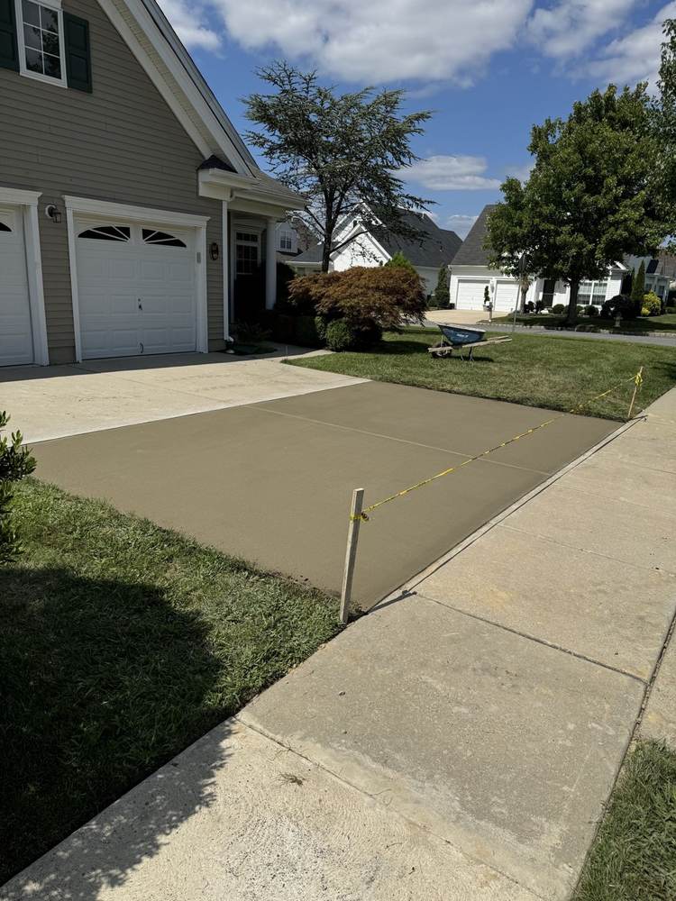 Fresh concrete driveway extension at a suburban home, taped off while curing by South Jersey Construction Enterprise