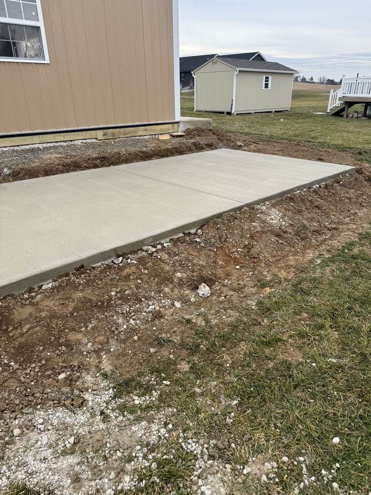 New concrete driveway installed by South Jersey Construction Enterprise to a garage, curing behind caution tape