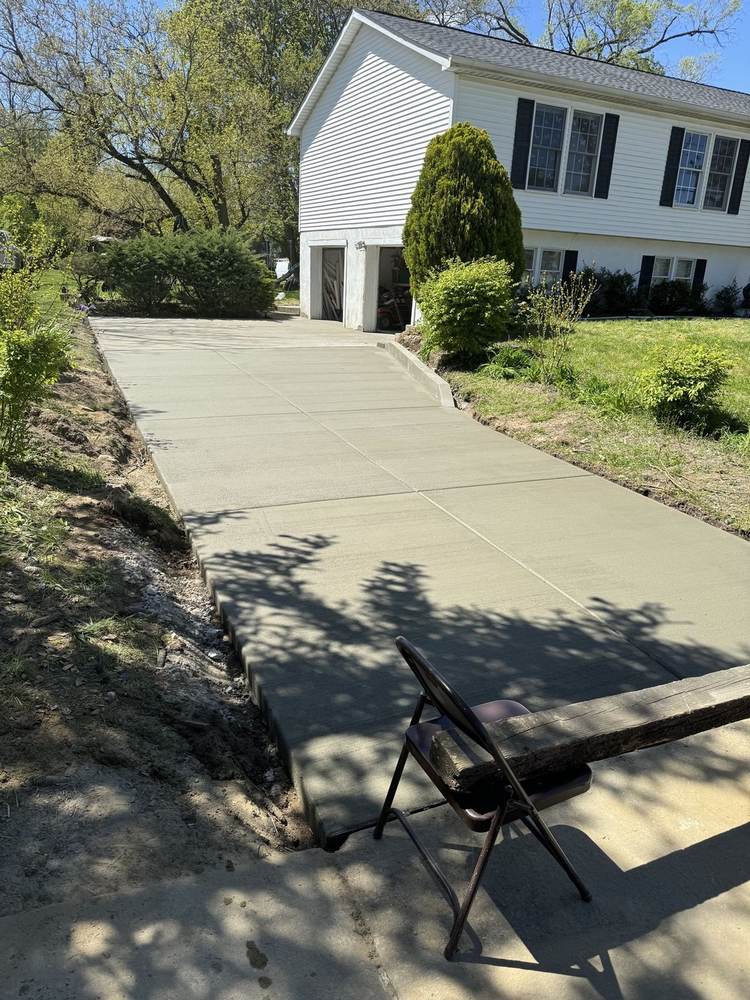 Fresh concrete driveway installed by South Jersey Construction Enterprise to a garage, curing behind caution tape
