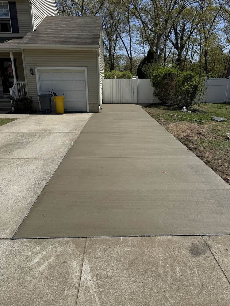 Concrete driveway extension beside a garage by South Jersey Construction Enterprise