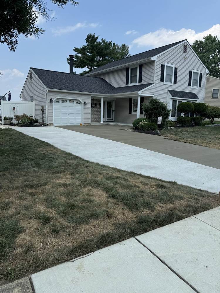 Concrete driveway leading to a garage at a suburban home by South Jersey Construction Enterprise