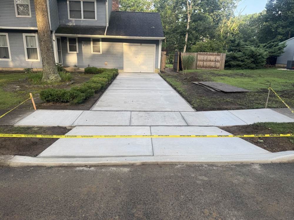 New concrete driveway and sidewalk leading to a garage by South Jersey Construction Enterprise