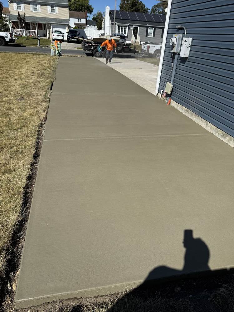 Long fresh concrete driveway beside a home, finished by South Jersey Construction Enterprise