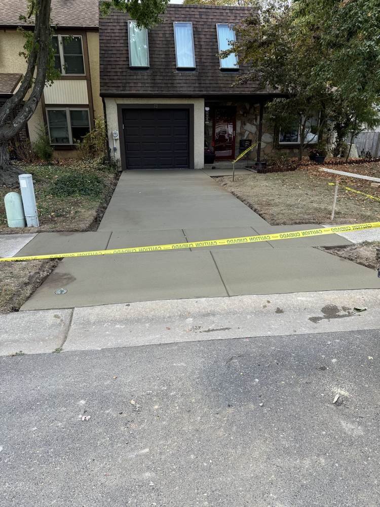 New concrete driveway leading to a townhouse garage by South Jersey Construction Enterprise