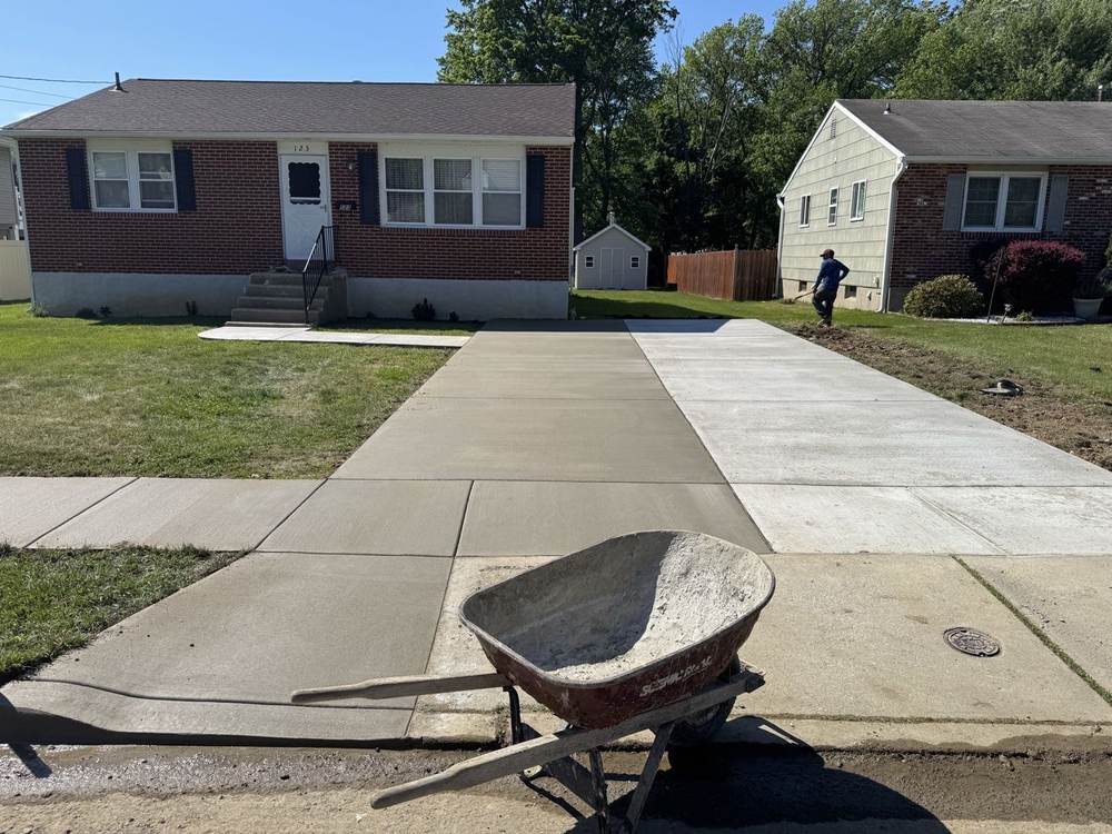 New concrete driveway with a wheelbarrow in the foreground, completed by South Jersey Construction Enterprise