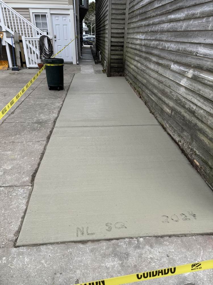 New concrete pad installed by South Jersey Construction Enterprise beside a building, with a shed in the background