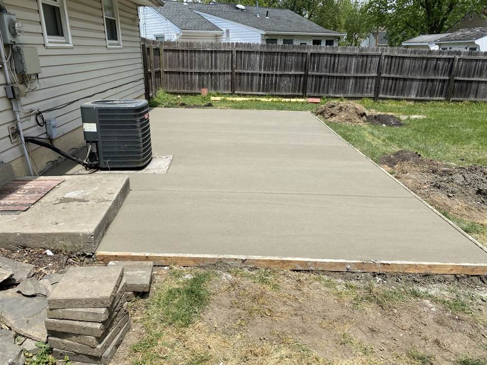 New concrete patio pad installed by South Jersey Construction Enterprise beside a house with an AC unit