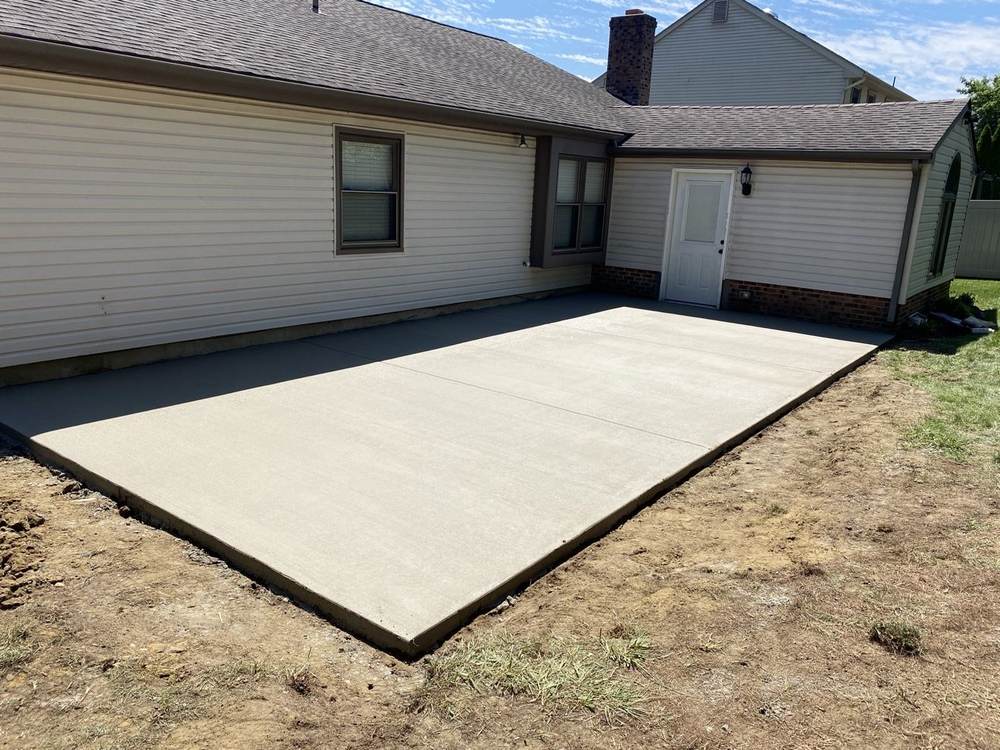 New concrete patio installed by South Jersey Construction Enterprise behind a beige house