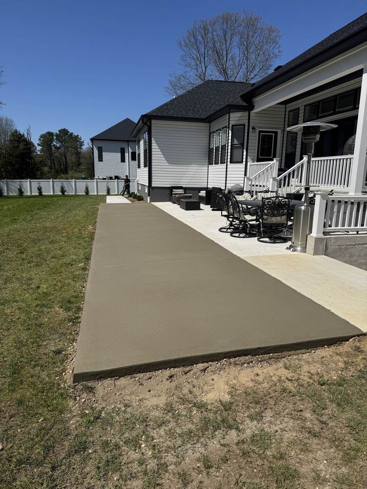 Concrete patio extension beside a house with porch furniture by South Jersey Construction Enterprise