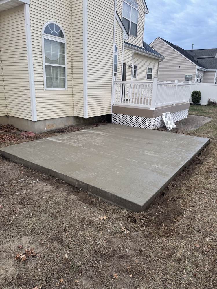 Concrete patio extension installed beside a raised deck by South Jersey Construction Enterprise