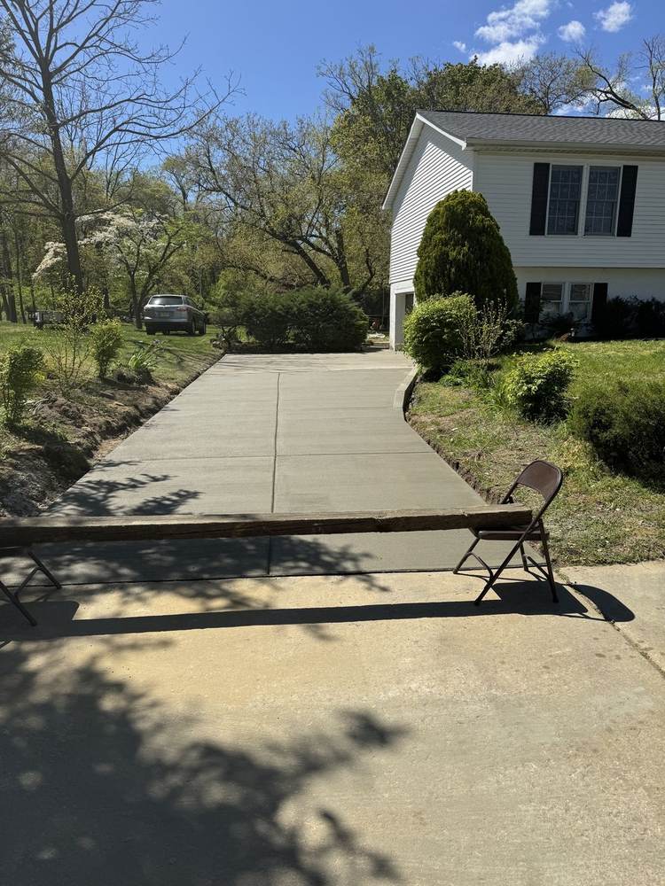 Fresh concrete patio with rounded edge installed by South Jersey Construction Enterprise beside a white house