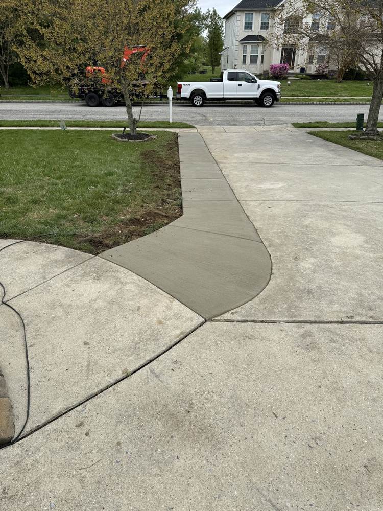 New concrete patio with steps to a side door installed by South Jersey Construction Enterprise beside a white house