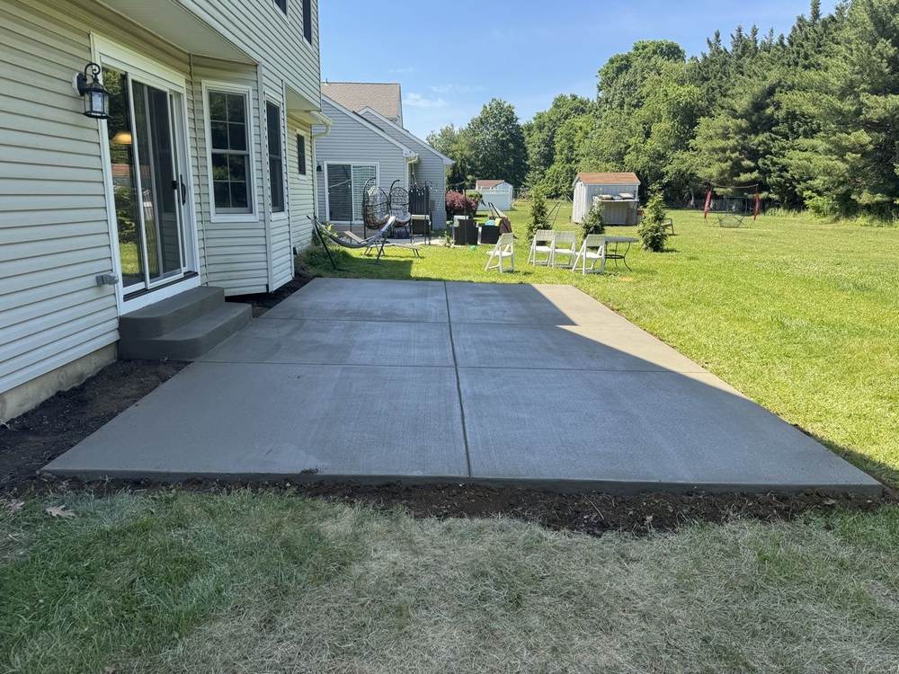 Backyard concrete patio with steps up to a sliding door by South Jersey Construction Enterprise