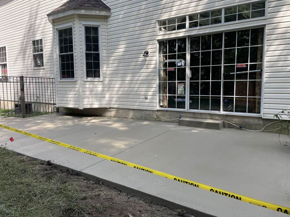 New concrete patio beside sliding glass doors by South Jersey Construction Enterprise