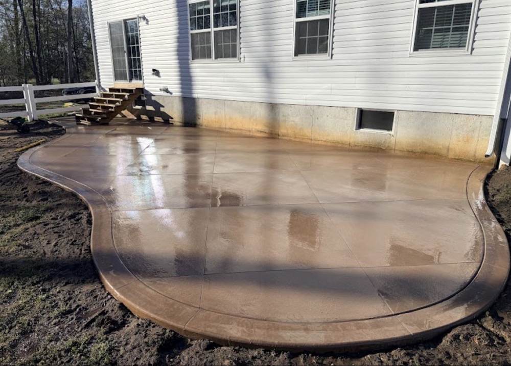 Stained and sealed curved concrete patio with a decorative border by South Jersey Construction Enterprise