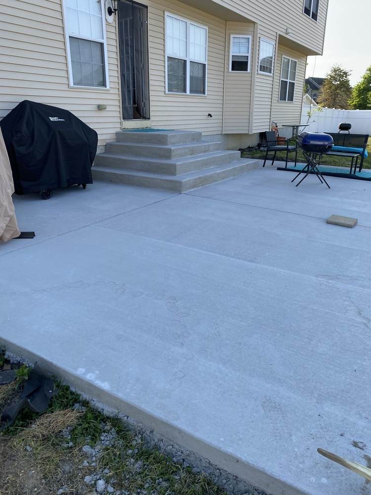 New concrete patio with steps installed by South Jersey Construction Enterprise at a beige house