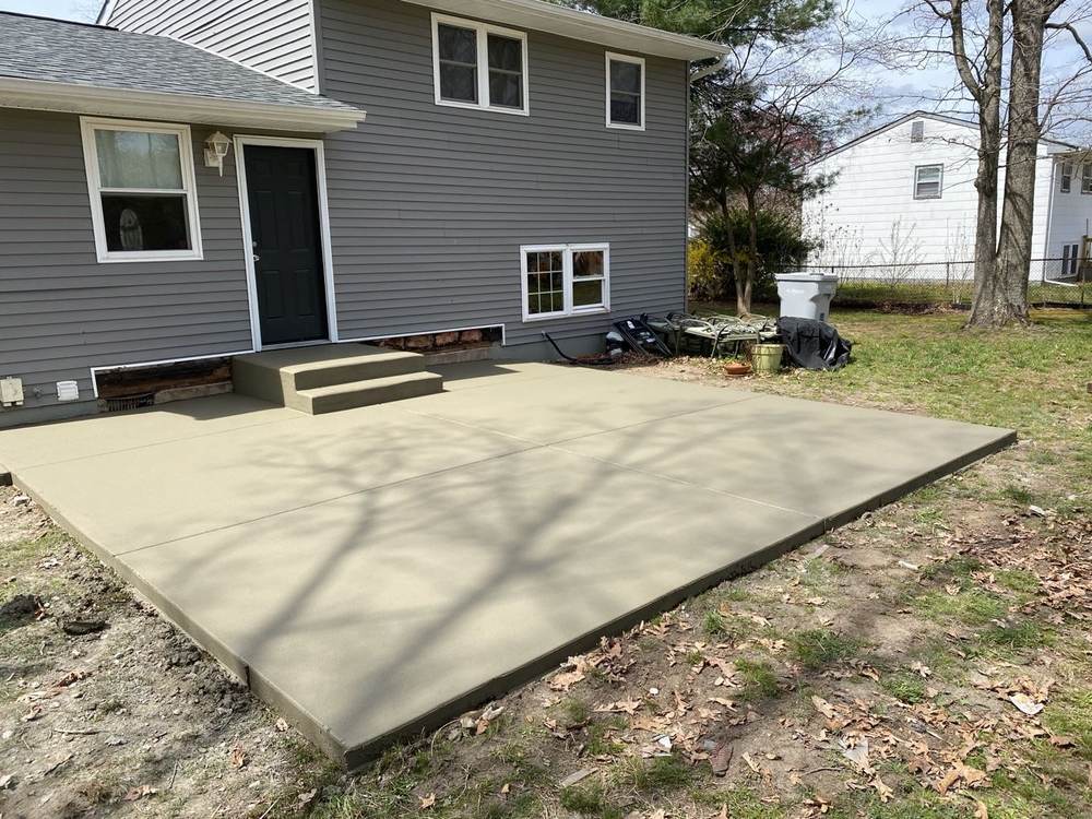 New concrete patio with steps installed by South Jersey Construction Enterprise at a gray house side door