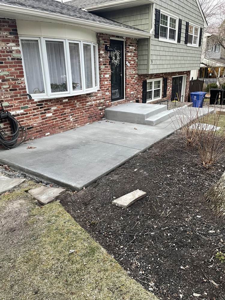 Large concrete patio installed beside a white vinyl fence by South Jersey Construction Enterprise
