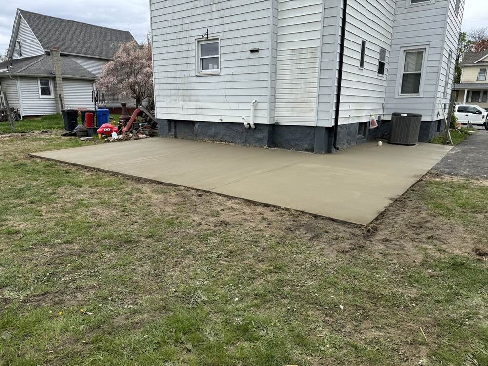 Concrete patio slab poured beside a white house by South Jersey Construction Enterprise