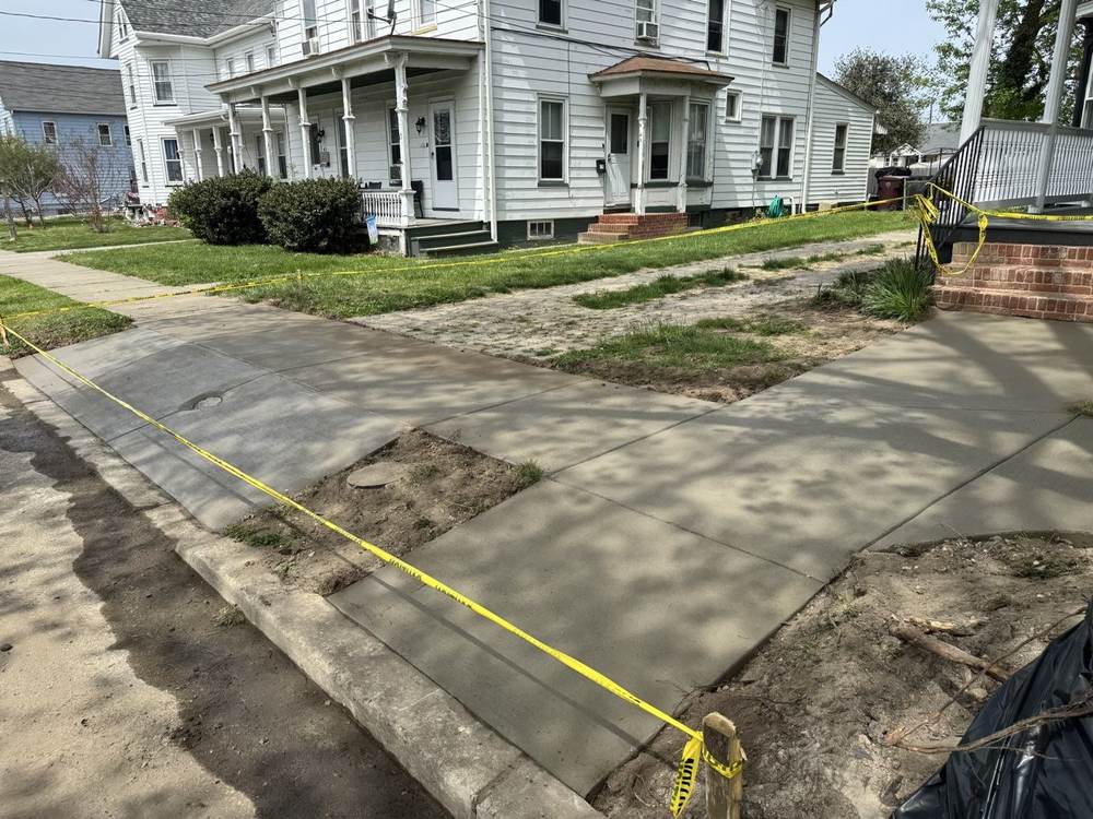 New concrete sidewalk in front of row houses with caution tape, by South Jersey Construction Enterprise