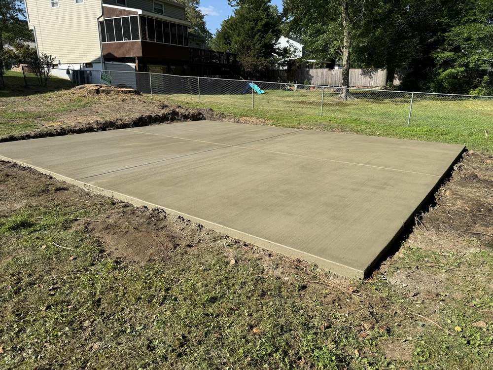 Large concrete slab pad freshly poured in a residential backyard by South Jersey Construction Enterprise