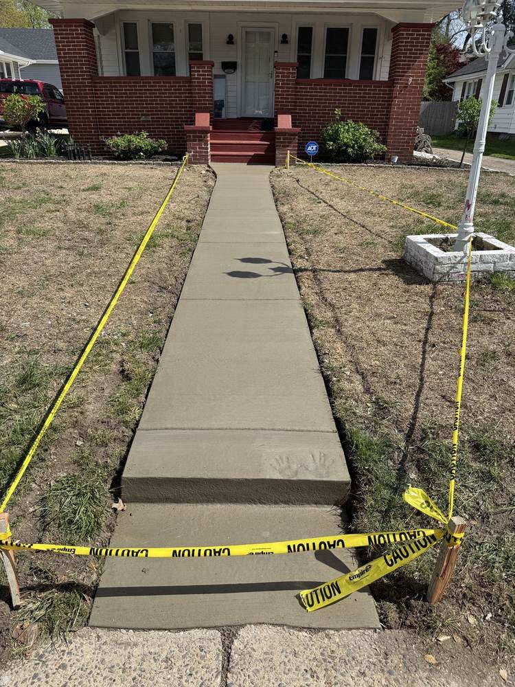 Concrete walkway with steps to a brick house, caution tape across the fresh pour, by South Jersey Construction Enterprise