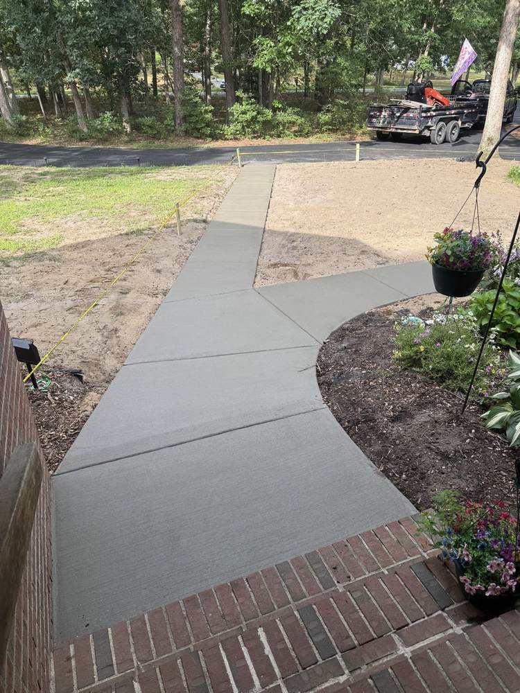 Curved concrete walkway with brick border by South Jersey Construction Enterprise