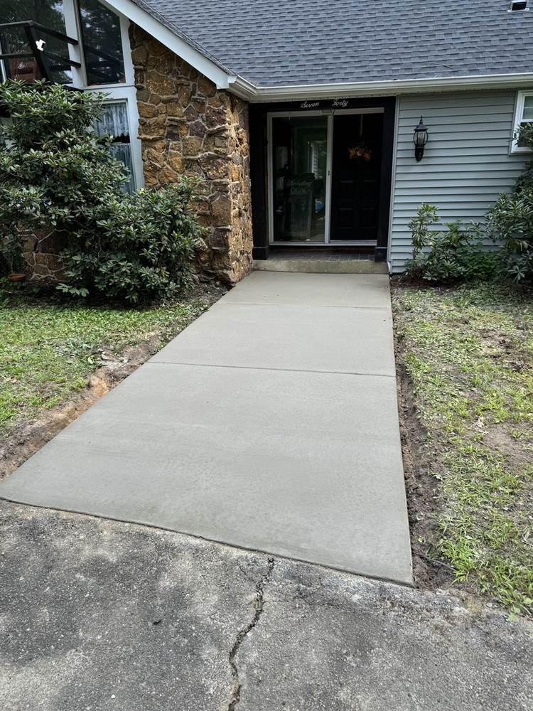 Concrete walkway leading to a front entrance with stone facade by South Jersey Construction Enterprise
